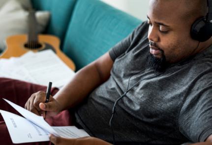 Un homme écoute un podcast avec un casque audio assis sur un canapé